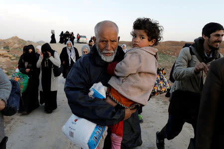 A displaced Iraqi man carries his granddaughter while fleeing his home, as Iraqi forces battle with Islamic State militants, in western Mosul, Iraq March 8, 2017. REUTERS/Zohra Bensemra