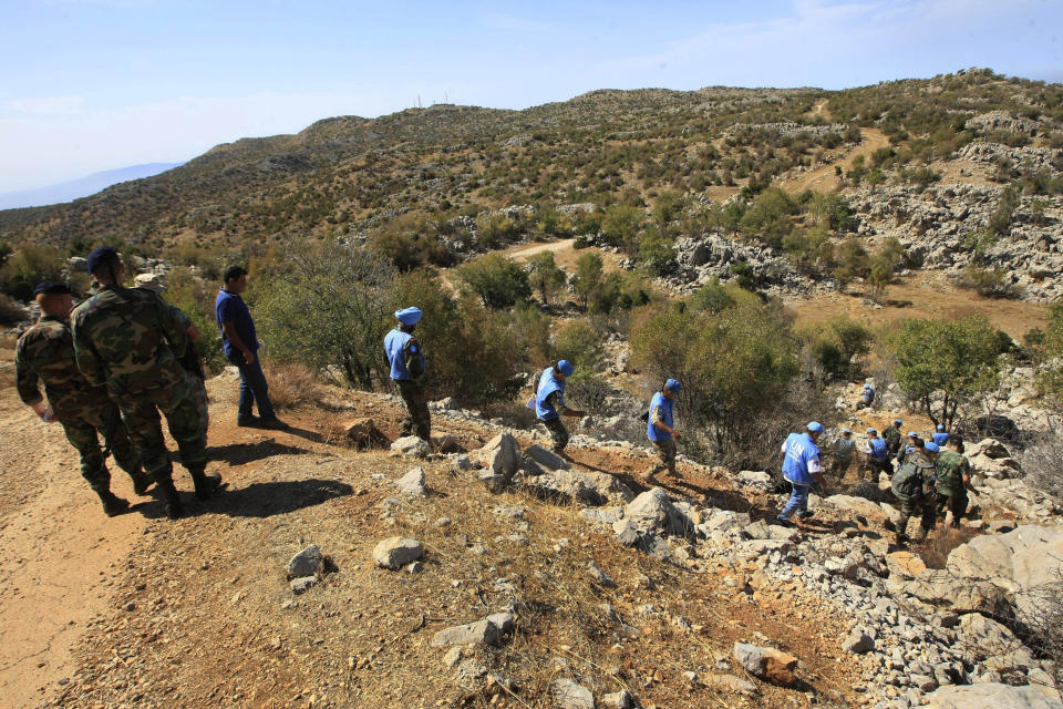 FILE - In this Oct. 8, 2014, file photo, Lebanese army soldiers and U.N. peacekeepers investigate near the site where Hezbollah had attacked on an Israeli patrol, in the hills of Kfar Shouba village, near the Israeli-occupied Shebaa farms, southern Lebanon. The militant Hezbollah group said it fired a barrage of rockets near Israeli positions close to the Lebanese border on Friday, Aug. 6, 2021, calling it retaliation for Israeli airstrikes on southern Lebanon a day earlier. (AP Photo/Mohammed Zaatari, File)