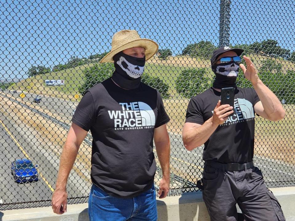 Masked men display a ‘Embrace White Pride’ banner over the Highway 101 overpass in Templeton, California on Saturday, May 13, 2023.