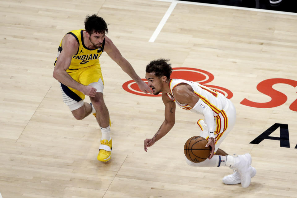 Atlanta Hawks guard Trae Young, right, drives to the basket around Indiana Pacers guard T.J. McConnel, left, during the second quarter of an NBA basketball game Saturday, Feb. 13, 2021, in Atlanta. (AP Photo/Butch Dill)