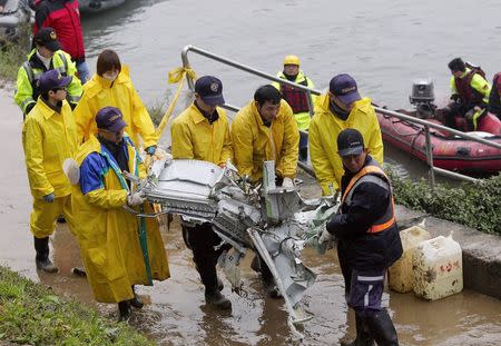 Rescue personnel carry the wreckage of TransAsia Airways plane Flight GE235 after it crash landed into a river, in New Taipei City February 5, 2015. REUTERS/Pichi Chuang