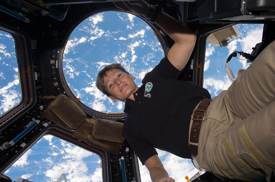 Astronaut Peggy Whitson floats in the cupola on board the International Space Station, backdropped by the Earth below.