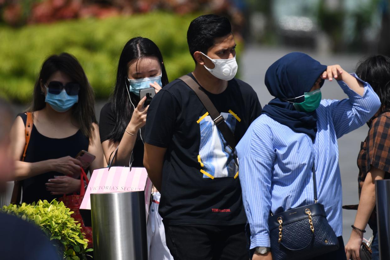 People wearing protective facemasks wait at a pedestrian crossing in Singapore on 4 February, 2020. (PHOTO: AFP via Getty Images)