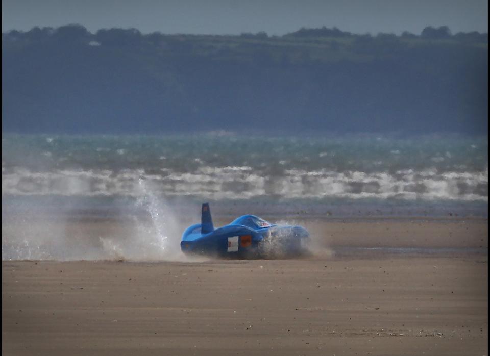 Driver Joe Wales crashes through the surf after veering off course during an attempt on the British land speed record for battery-powered vehicles in the Bluebird Electric on Pendine Sands on August 14, 2011 in Pendine, Wales. Driver Joe Wales and his father, fellow driver Don Wales, come from a famous family who have been setting land and water speed records since 1924. Don holds the current UK record of 137 miles an hour in an electric vehicle.