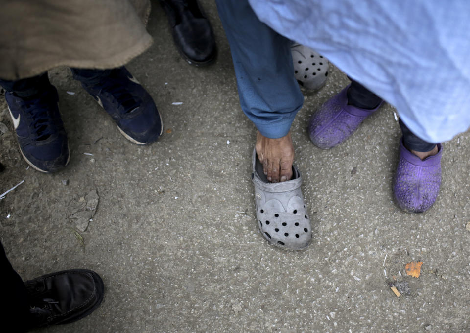 CORRECTING YEAR TO 2018 - In this Sunday, Nov. 18, 2018 photo a view of the feet of migrants as they wait for food distribution at a camp in Velika Kladusa, Bosnia, close to the border to Croatia. The approach of the tough Balkan winter spells tough times for the migrants that remain stuck in the region while trying to reach Western Europe, with hundreds of them staying in make-shift camps with no heating or facilities.(AP Photo/Amel Emric)