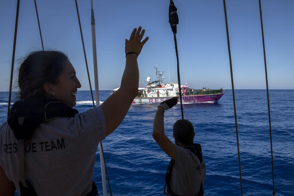 Members of the Astral crew, a rescue ship from the Spanish NGO Open Arms, wave at Louise Michel rescue vessel, a former French patrol boat currently manned by activists and funded by the renowned artist Banksy, in the Central Mediterranean sea, at 50 miles south from Lampedusa, Friday, Aug. 28, 2020. A Berlin-based group says it has begun migrant rescue operations in the Mediterranean Sea with a bright pink former navy vessel sponsored by British artist Banksy. The group operating the MV Louise Michel, a sleek 30-meter (98-foot) ship named after a 19th century French feminist and anarchist, said late Thursday that it rescued 89 from an inflatable boat in distress. (AP Photo/Santi Palacios)