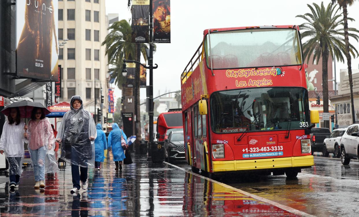 People walk on Hollywood Boulevard during a heavy downpour on 19 February 2024 (Getty Images)