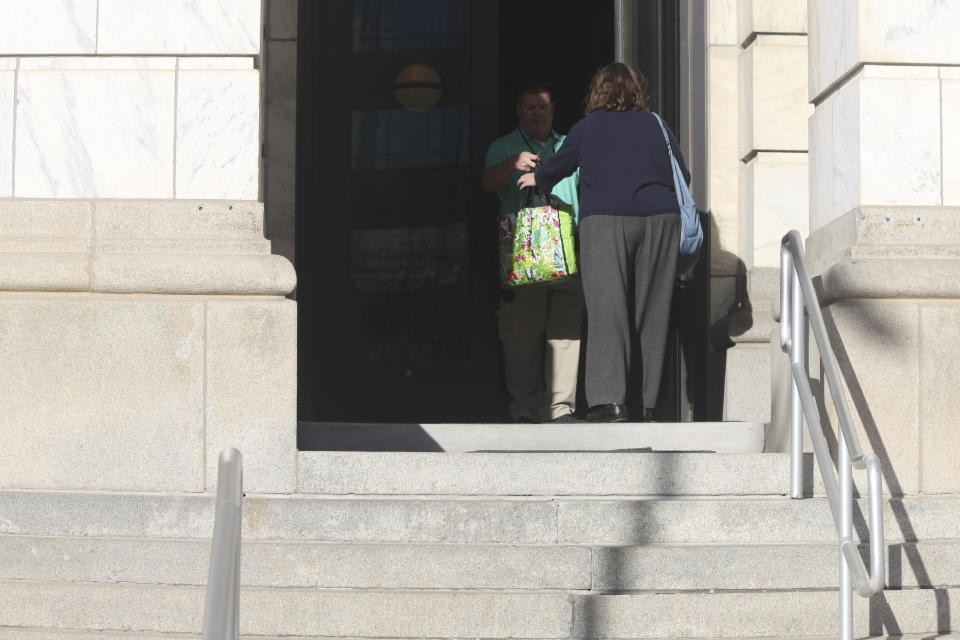 A law enforcement officer inside the building that houses the Kansas secretary of state's office hands a bag to a worker who has come to retrieve it after the building was evacuated because the office received suspicious mail, Tuesday, Nov. 14, 2023, in Topeka, Kan. The incident came less than a week after election offices in at least five other states received threatening mail. (AP Photo/John Hanna)