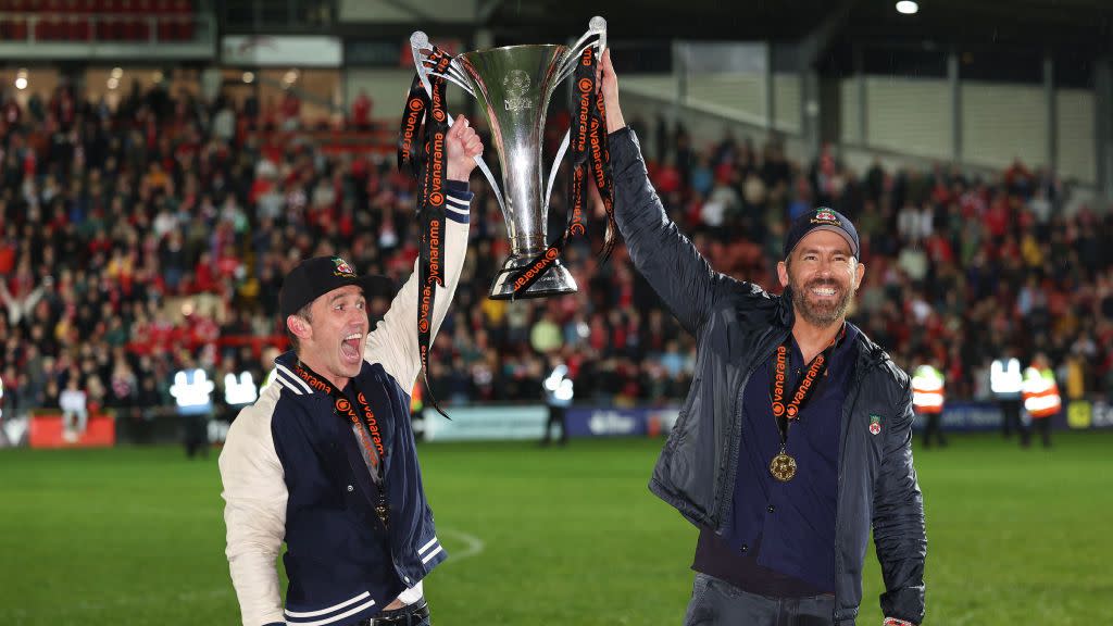 rob mcelhenney and ryan reynolds hold the wrexham trophy