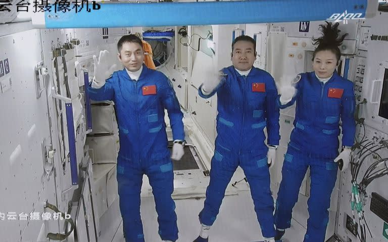 Los tres astronautas chinos Ye Guangfu, Zhai Zhigang y Wang Yaping (de izquierda a derecha) saludan al entrar a la nueva estación espacial