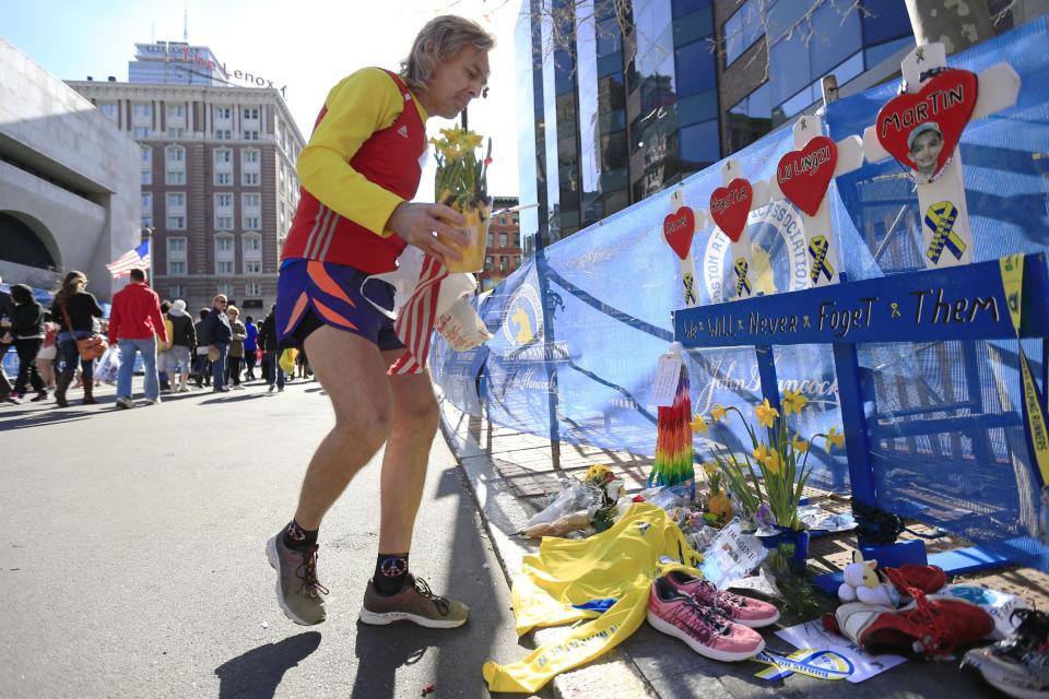 Ron McCracken of Dallas pays his respects at a makeshift memorial honoring to the victims of the 2013 Boston Marathon bombings ahead of Monday's 118th Boston Marathon, Sunday, April 20, 2014, in Boston. McCracken's race last year was cut short due to bombings and Monday's race will mark his 14th year running in the Boston Marathon. The memorial is where the first of two explosions happened last year near the finish line. (AP Photo/Matt Rourke)