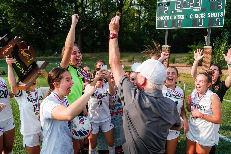 Grosse Pointe North assistant coach Marty Shearer, center, celebrates with players after shoot-out win over East Grand Rapids at MHSAA Division 2 girls soccer state final at DeMartin Soccer Complex in East Lansing on Friday, June 16, 2023.