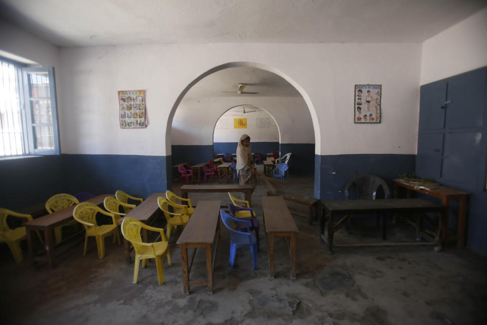 A Kashmiri school staff member cleans a deserted classroom in Srinagar, Indian controlled Kashmir, Monday, Aug. 19, 2019. Restrictions continue in much of Indian-administered Kashmir, despite India's government saying it was gradually restoring phone lines and easing a security lockdown that's been in place for nearly two weeks. (AP Photo/Mukhtar Khan)