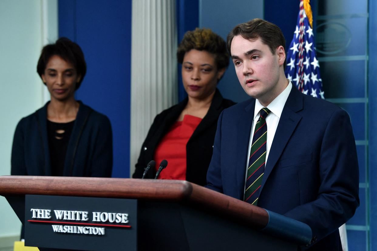 Andrew Bates speaks into a microphones at a podium with plaque that reads the White House, Washington in front of Director of the Office of Management and Budget Shalanda Young and Chair of the Council of Economic Advisers Cecilia Rouse.