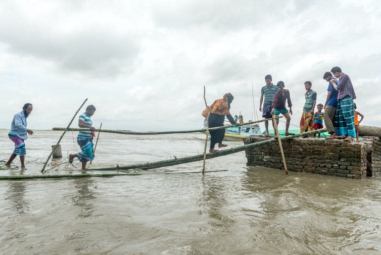 People cross a wooden bridge to escape flood water.