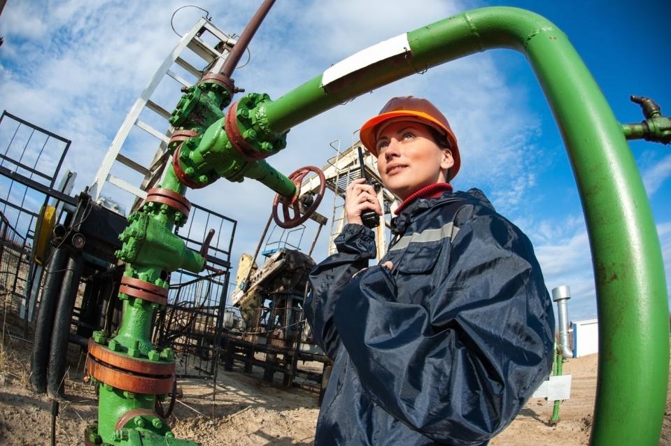 An engineer using a walkie-talkie while standing next to pipeline infrastructure. 
