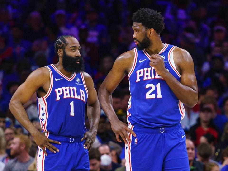 James Harden stands next to Joel Embiid during a game.