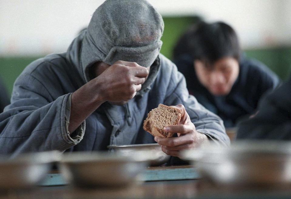 FILE – An unidentified prisoner holds a piece of bread inside Corrective Labor Colony No. 22 in the village of Leplei, some 600 kilometers (375 miles) southeast of Moscow, on Nov. 13, 1996. Former inmates, their relatives and human rights advocates paint a bleak picture of Russia’s prison system that is descended from the USSR's gulag. For political prisoners, life inside is a grim reality of physical and psychological pressure. (AP Photo/Alexander Zemlianichenko, File)