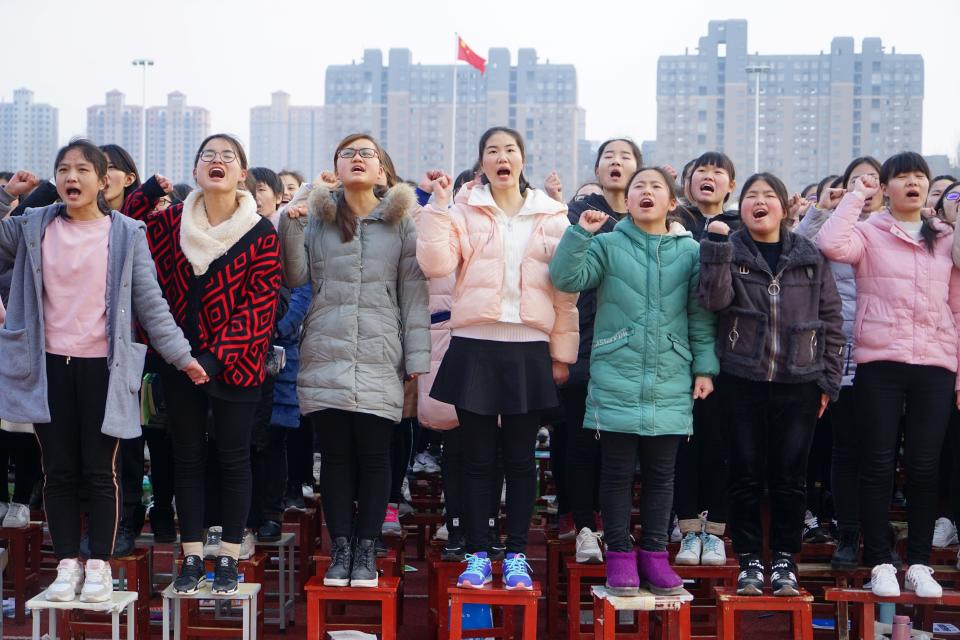 Students stand on chairs as they cheer at an oath-taking rally for the annual national entrance examinations, or "gaokao" in June, at a high school in Zhumadian, Henan province, China February 27, 2019. Picture taken February 27, 2019.