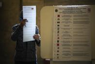 A man reads his ballot at a polling station during the Parliamentary elections in Moscow, Russia, Sunday, Sept. 19, 2021. Russia has begun the third day of voting for a new parliament that is unlikely to change the country's political complexion. There's no expectation that United Russia, the party devoted to President Vladimir Putin, will lose its dominance in the State Duma. (AP Photo/Alexander Zemlianichenko)