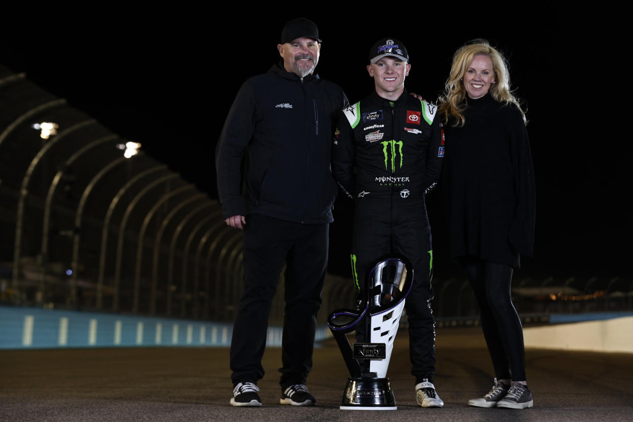 AVONDALE, ARIZONA - NOVEMBER 05: Ty Gibbs, driver of the #54 Monster Energy Toyota, poses with his father, Coy Gibbs and mother, Heather Gibbs after winning the NASCAR Xfinity Series Championship at Phoenix Raceway on November 05, 2022 in Avondale, Arizona. (Photo by Meg Oliphant/Getty Images)