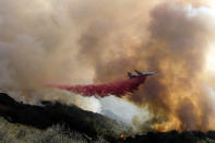 An air tanker drops retardant on a wildfire Wednesday, Oct. 13, 2021, in Goleta, Calif. A wildfire raging through Southern California coastal mountains threatened ranches and rural homes and kept a major highway shut down Wednesday as the fire-scarred state faced a new round of dry winds that raise risk of flames. The Alisal Fire covered more than 22 square miles (57 square kilometers) in the Santa Ynez Mountains west of Santa Barbara. (AP Photo/Ringo H.W. Chiu)