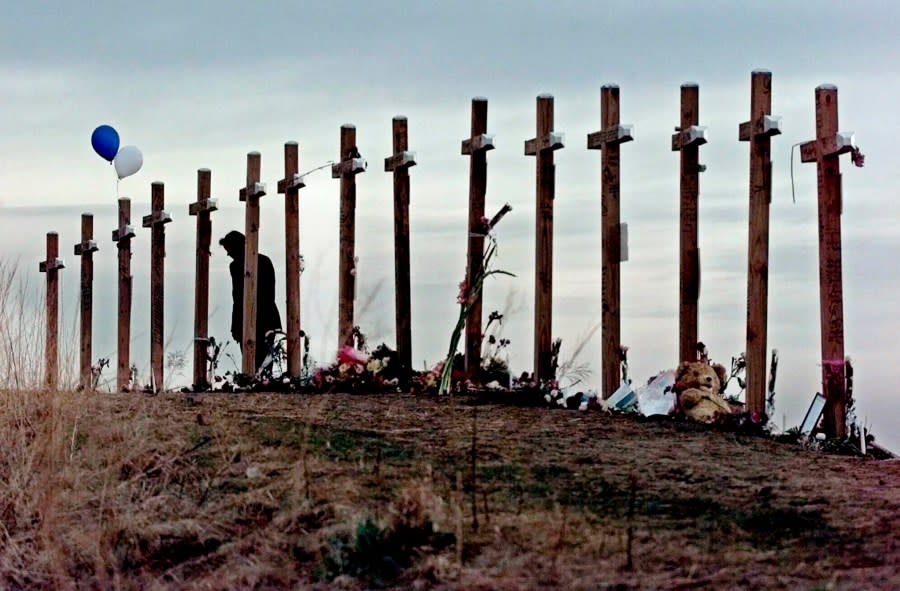 FILE – A woman stands among crosses posted on a hill above Columbine High School in Littleton, Colo., in remembrance of the people who died during a school shooting on April 20, 1999. (AP Photo/Eric Gay, File)