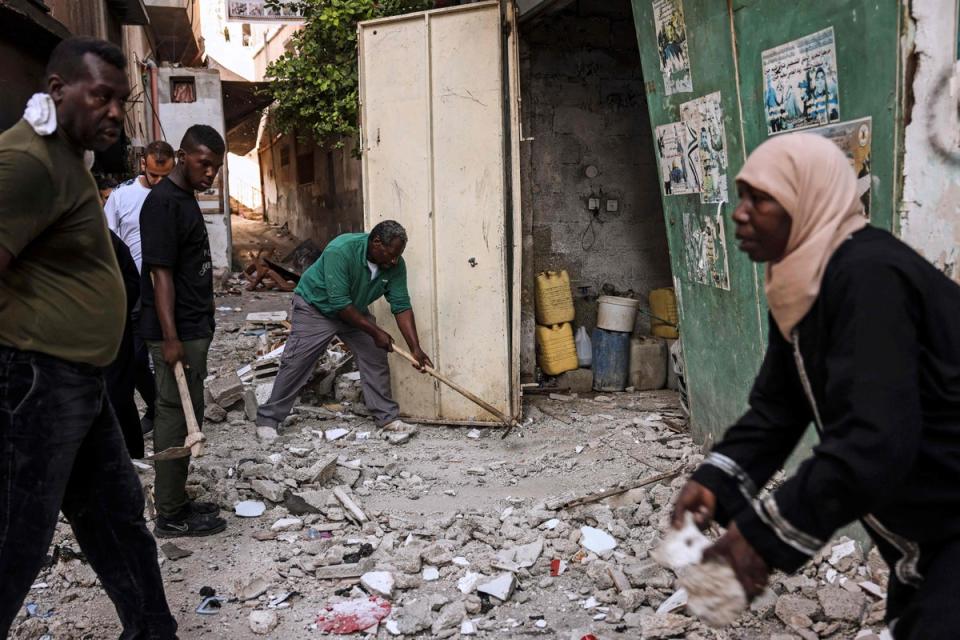 People clean up debris in the aftermath of the military operation (AFP via Getty Images)