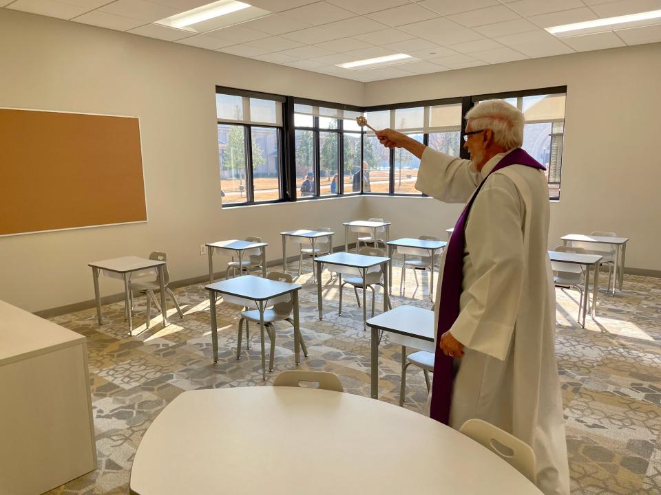 The Rev. Thomas Peyton, a former pastor at St. Teresa of Avila Catholic Church who helped lay the groundwork for the parish's building program, uses an aspergillum to bless with holy water one of the newly-built classrooms at the church in Grovetown.