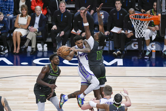 Sacramento Kings guard Malik Monk (0) collides with Minnesota Timberwolves center Naz Reid (11) as he goes up for a shot, while guard Anthony Edwards (1) watches during the second half of an NBA basketball game Saturday, Jan. 28, 2023, in Minneapolis. The Timberwolves won 117-110. (AP Photo/Craig Lassig)