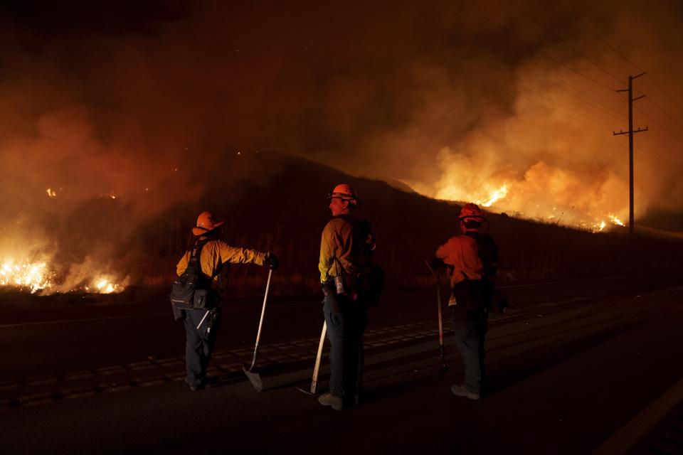 FILE - Firefighters monitor as flames consume brush along Gilman Springs Road during the Rabbit Fire, July 14, 2023, in Moreno Valley, Calif. More Americans believe they've personally felt the impact of climate change because of recent extreme weather according to new polling from The Associated Press-NORC Center for Public Affairs Research. (AP Photo/Eric Thayer, File)