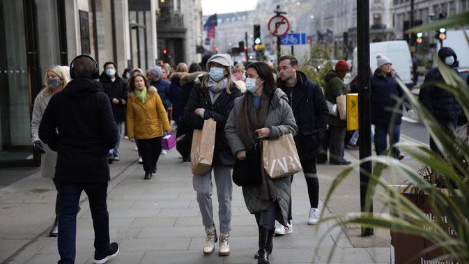 Orang-orang berjalan dengan tas belanjaan di Regent Street di London, Senin (29/11/2021). Di Inggris, kewajiban mengenakan masker akan berlaku lagi di toko-toko dan transportasi umum mulai Selasa menyusul temuan Covid-19 varian Omicron. (AP Photo/Matt Dunham)