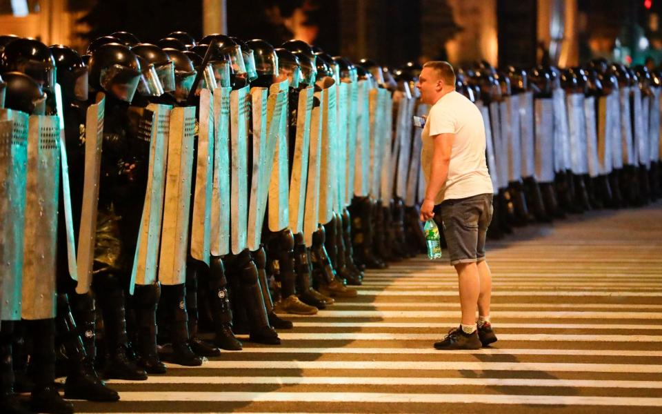 A protester speaks to police as they block the road during a rally  - AP