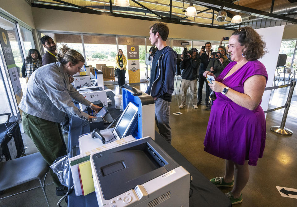 Luke Hoffman, 18, center, waits to receive his ballot as he stands with his mother, U.S. Senate candidate and U.S. Rep. Katie Porter, right, in the vote center at the University Hills Community Center in Irvine, Calif., Saturday, March 2, 2024. Porter was dropping off her ballot and Luke was voting for the first time. (Mark Rightmire/The Orange County Register via AP)