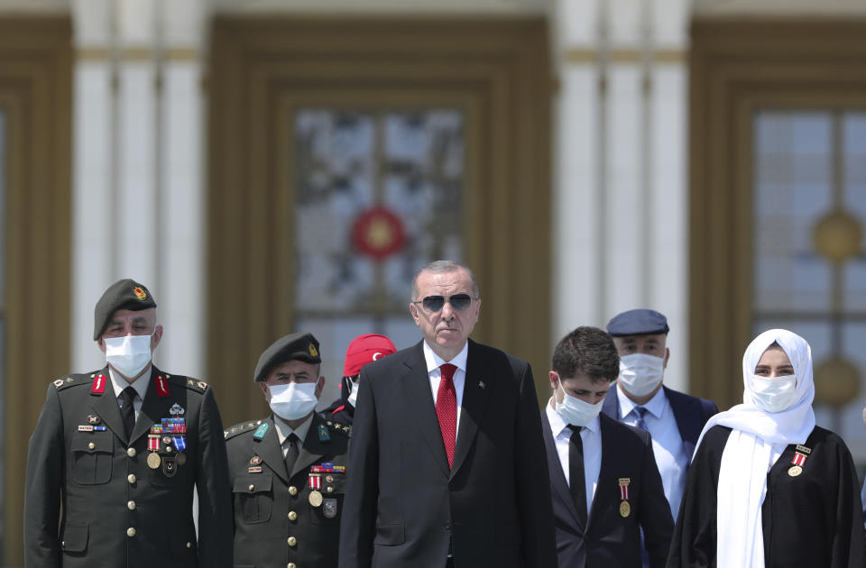 Turkey's President Recep Tayyip Erdogan and family members of coup victims walk to place flowers by the "Martyrs Monument" outside his presidential palace, in Ankara, Turkey, Wednesday, July 15, 2020. Turkey is marking the fourth anniversary of the July 15 failed coup attempt against the government, with prayers and other events remembering its victims.(Turkish Presidency via AP, Pool)