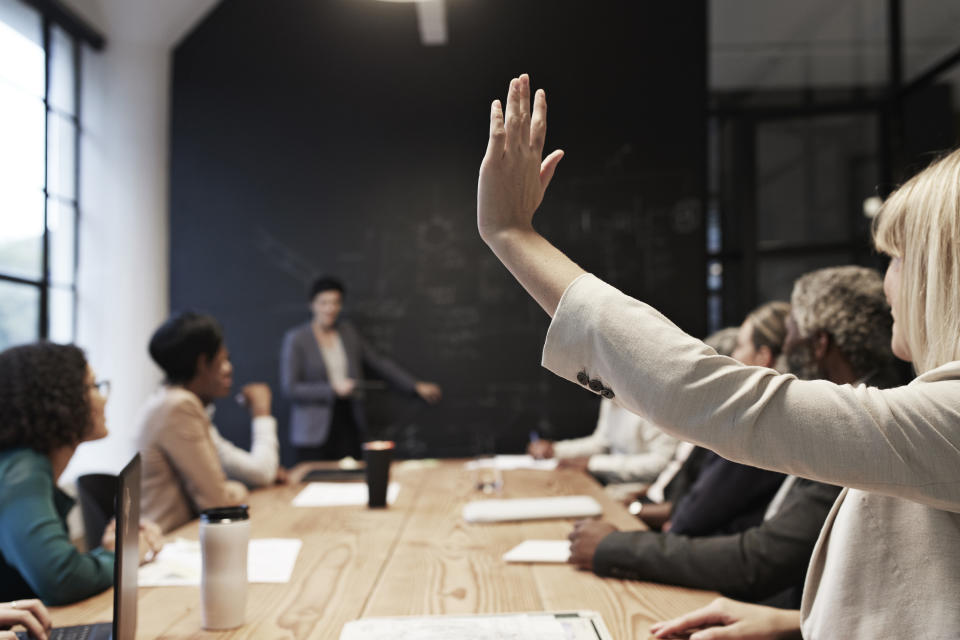 person raising their hand in a meeting