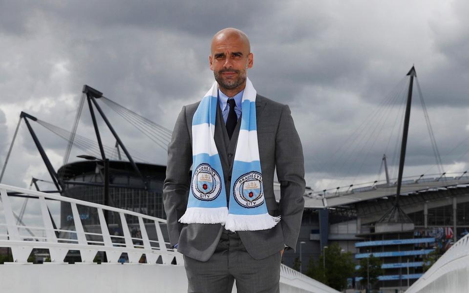 Pep Guardiola poses in grey suit outside City of Manchester Stadium - REUTERS