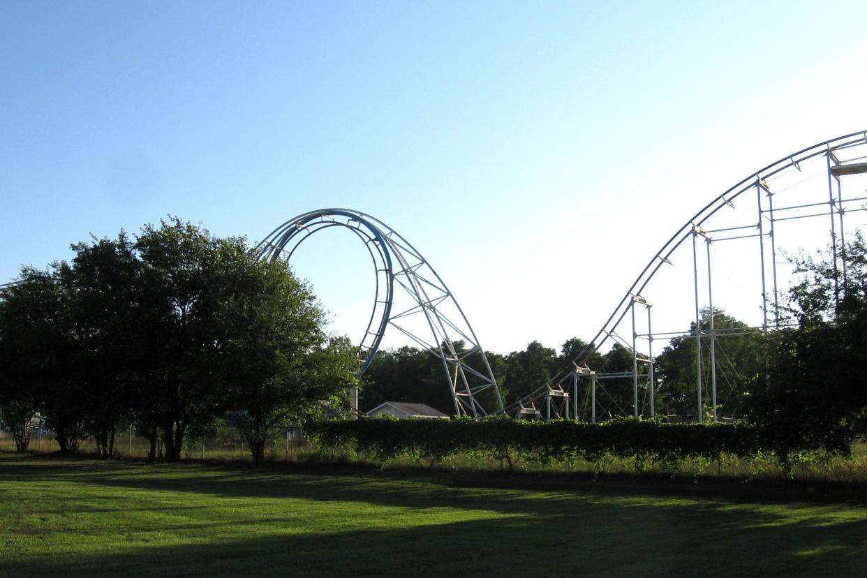 Abandoned Fun Spot Amusement Park & Zoo, Angola, Indiana, afterburner rollercoaster, grass in the foreground, trees in the background, a bright blue sky, in summer