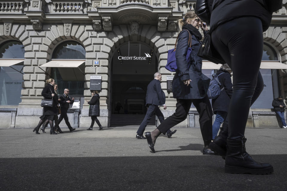 People walk past the entrance of Swiss bank Credit Suisse at their headquarters in Zurich, Switzerland, Thursday March 16, 2023. Credit Suisse's shares soared 30% on Thursday after it announced it will move to shore up its finances by borrowing up to nearly $54 billion from the Swiss central bank, bolstering confidence as fears about the banking system moved from the U.S. to Europe. (Ennio Leanza/Keystone via AP)