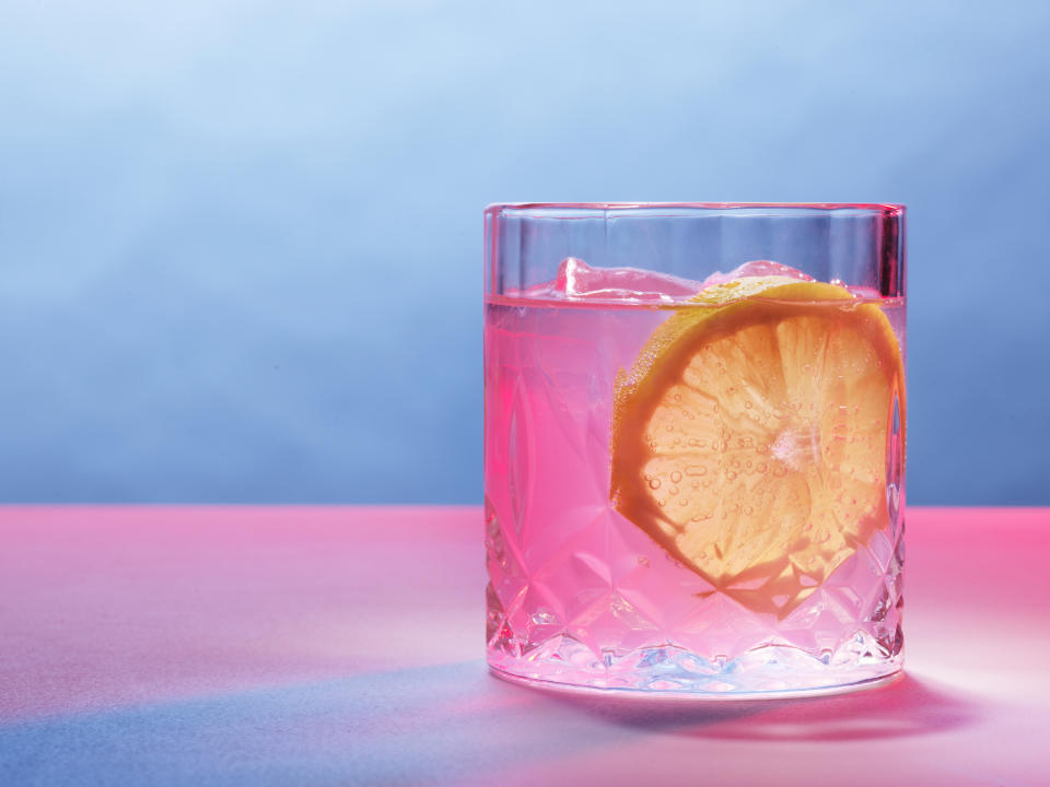 Glass with a beverage and lemon slice on a reflective surface