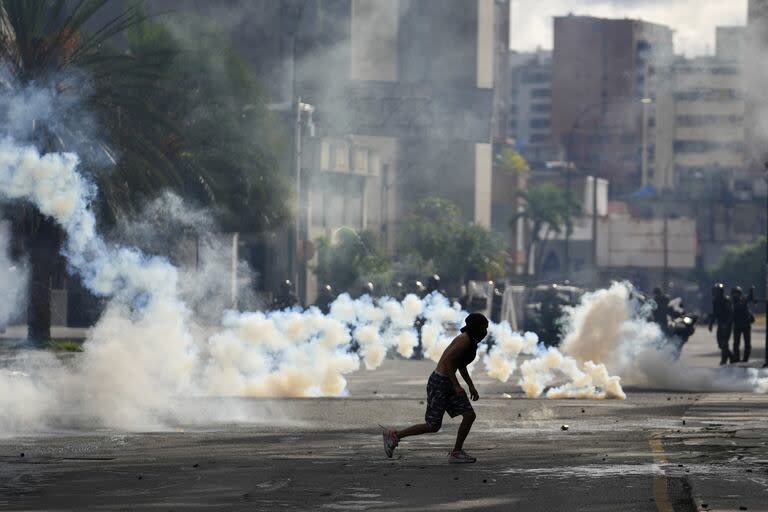 Un manifestante corre mientras la policía arroja gas durante las manifestaciones contra los resultados oficiales de las elecciones que declaran la reelección del presidente Nicolás Maduro, el día después de la votación en Caracas.