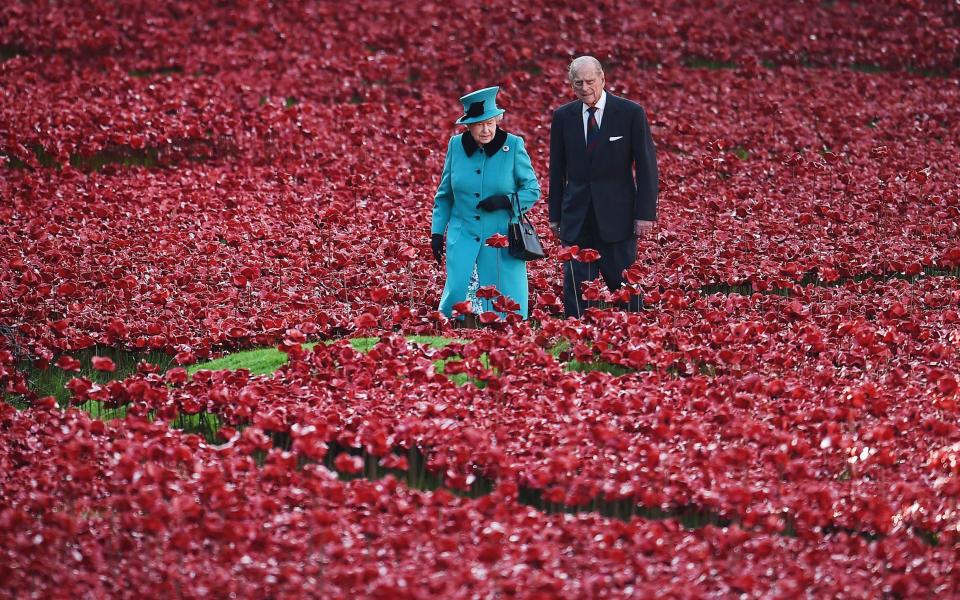 The Queen and the late Prince Philip, Duke of Edinburgh walking among ceramic red poppies planted in memory of the British and Commonwealth dead from WWI in the moat at the Tower of London on October 16, 2014 - Andy Rain/PA-EFE/Shutterstock