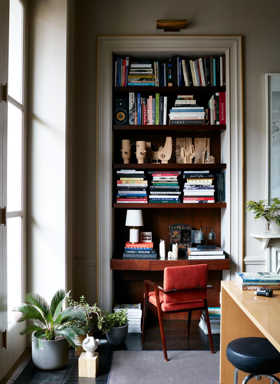 The picture light above the bookcase is a Thomas O'Brien David in brass by Visual Comfort. The study's 1950s rosewood chairs were reupholstered in red-orange linen from Gaston y Daniela at Kravet.