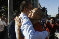 Theary Seng, right, a Cambodian-American lawyer, dressed in a prison-style orange outfit, hugs her supporter as she arrives at Phnom Penh Municipal Court in Phnom Penh, Cambodia, Tuesday, Jan. 4, 2022. Cambodian security forces on Tuesday briefly detained Theary Seng, a prominent rights activist, as she walked barefoot near the prime minister’s residence in Phnom Penh, wearing the orange outfit and Khmer Rouge-era ankle shackles. She was released, shortly afterwards, and arrived at the Phnom Penh court for the resumption of her trial on treason charges. (AP Photo/Heng Sinith)