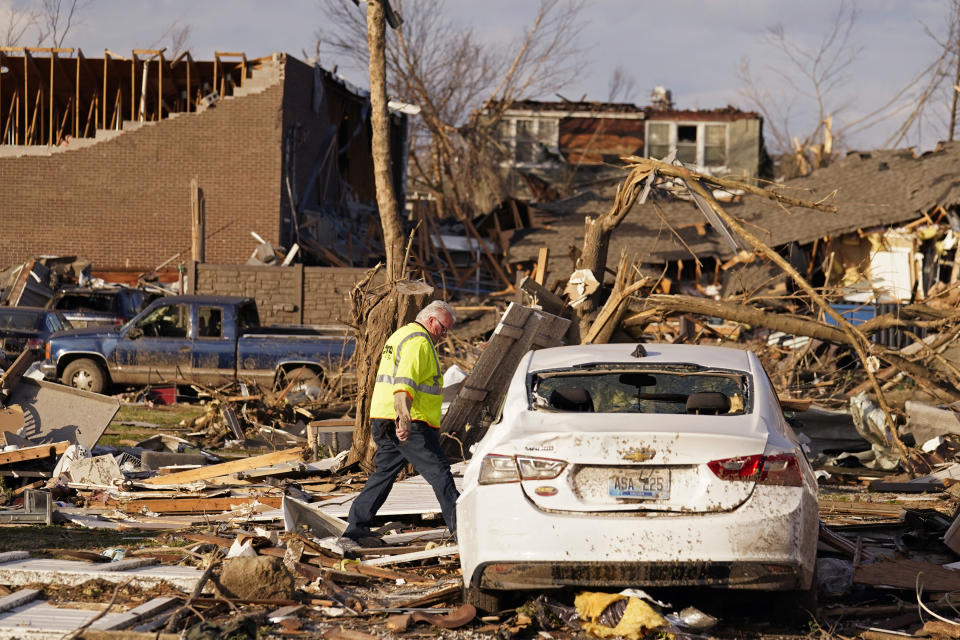 An Atmos Energy employee walks amid destruction as he checks the integrity of gas meters after the gas main was shut off, in the aftermath of tornadoes that tore through the region, in Mayfield, Ky., Tuesday, Dec. 14, 2021. (AP Photo/Gerald Herbert)