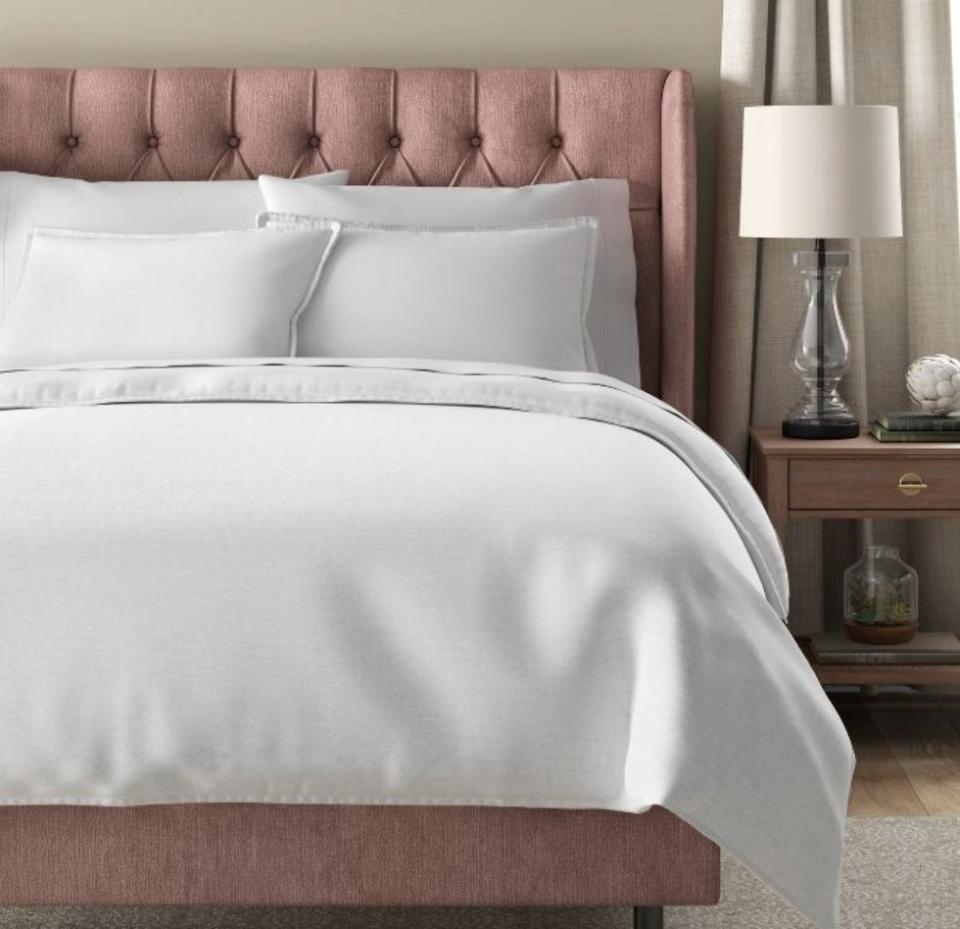 A pink bed with white linens