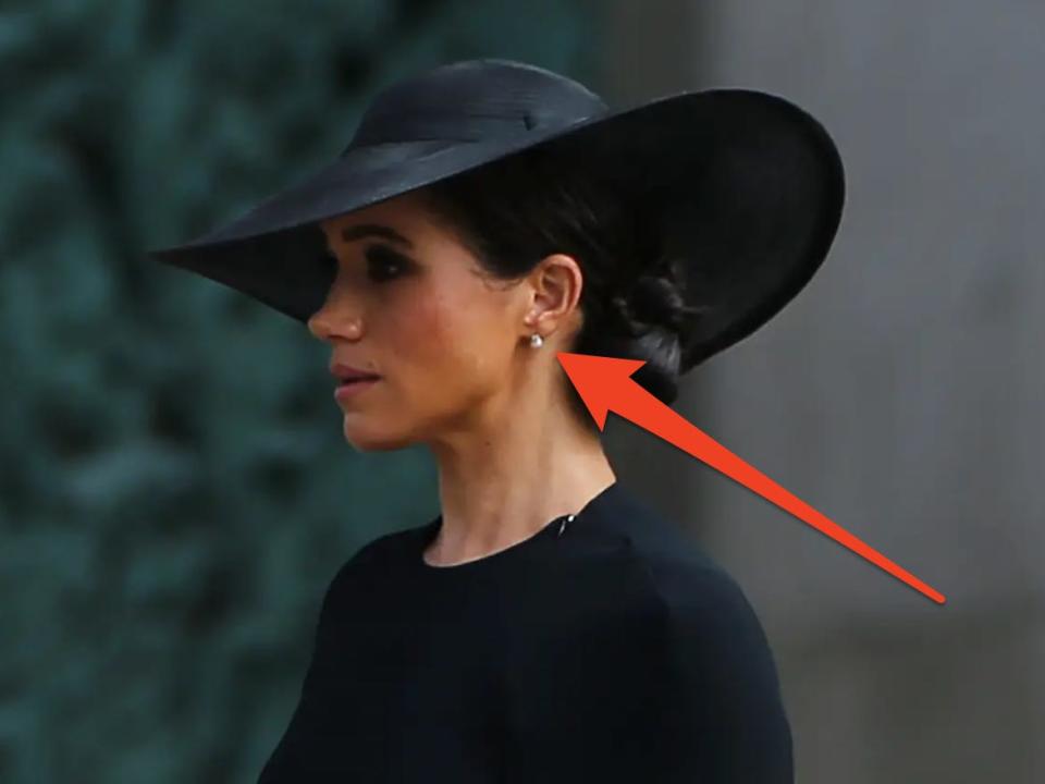 Meghan Markle in black dress and hat at Queen Elizabeth II’s funeral wearing pearl earrings  (and red arrow pointed to them)