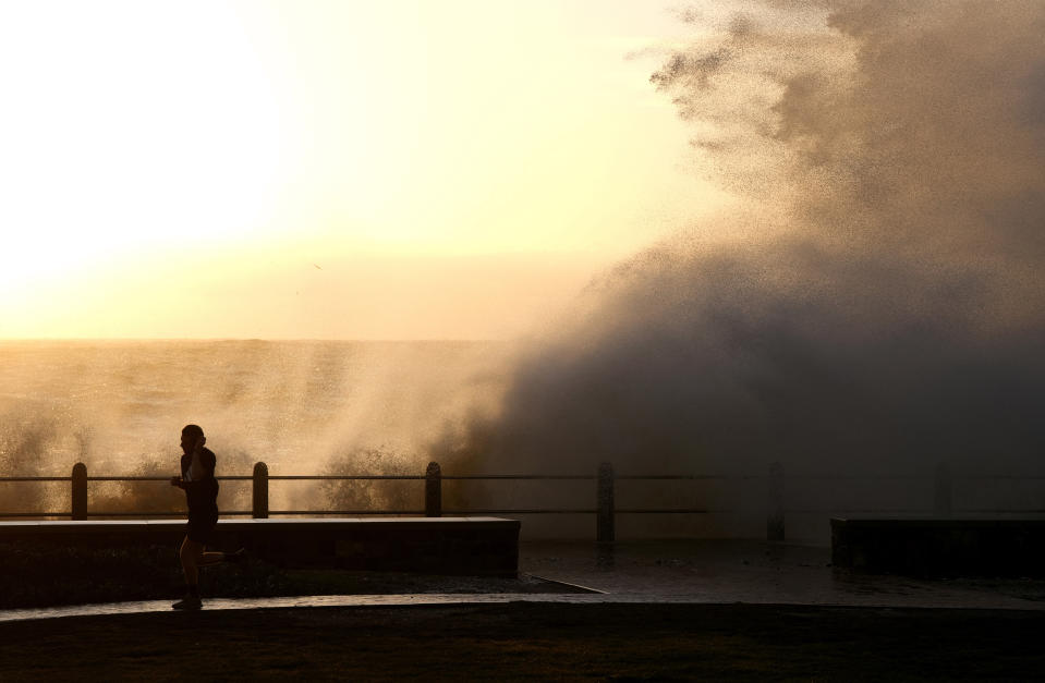 Waves break over Sea Point's promenade in Cape Town, South Africa, Monday, July 8, 2024. City authorities say nearly 1,000 homes in informal settlements around the city have been destroyed by gale-force winds, displacing around 4,000 people with multiple cold fronts expected until at least Friday. (AP Photo/Nardus Engelbrecht)