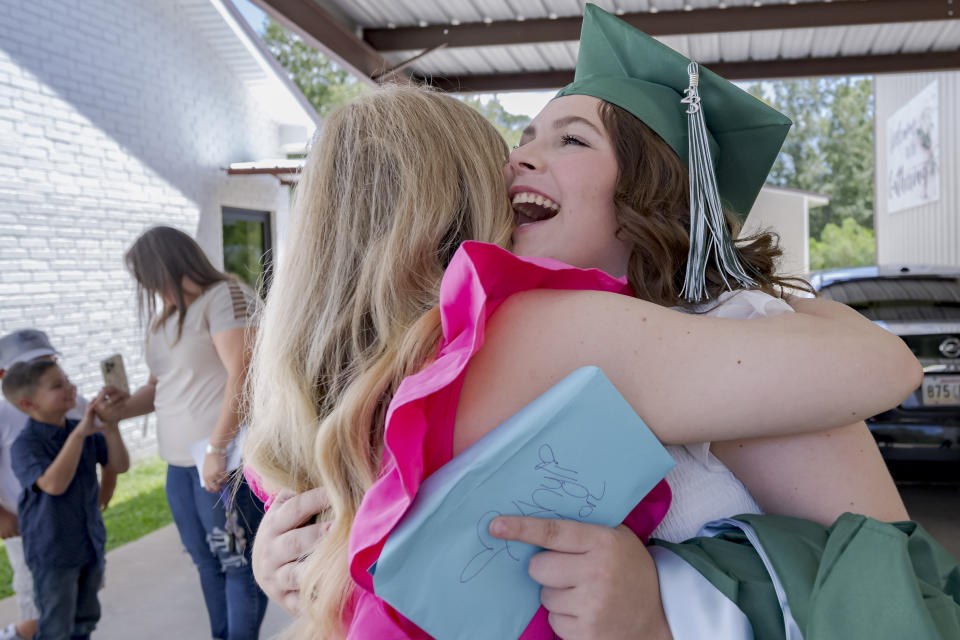 Khyli Barbee, 15, wearing mortar cap, is hugged by her mother, Brittany Barbee, after graduating with the class of Springfield Preparatory School at Victory in Christ church in Holden, La., Saturday, Aug. 5, 2023. Nearly 9,000 private schools in Louisiana don’t need state approval to grant degrees. Non-approved schools make up a small percentage of the state total. But the students in Louisiana’s off-the-grid school system are a rapidly growing example of the national fallout from COVID-19 — families disengaging from traditional education. (AP Photo/Matthew Hinton)