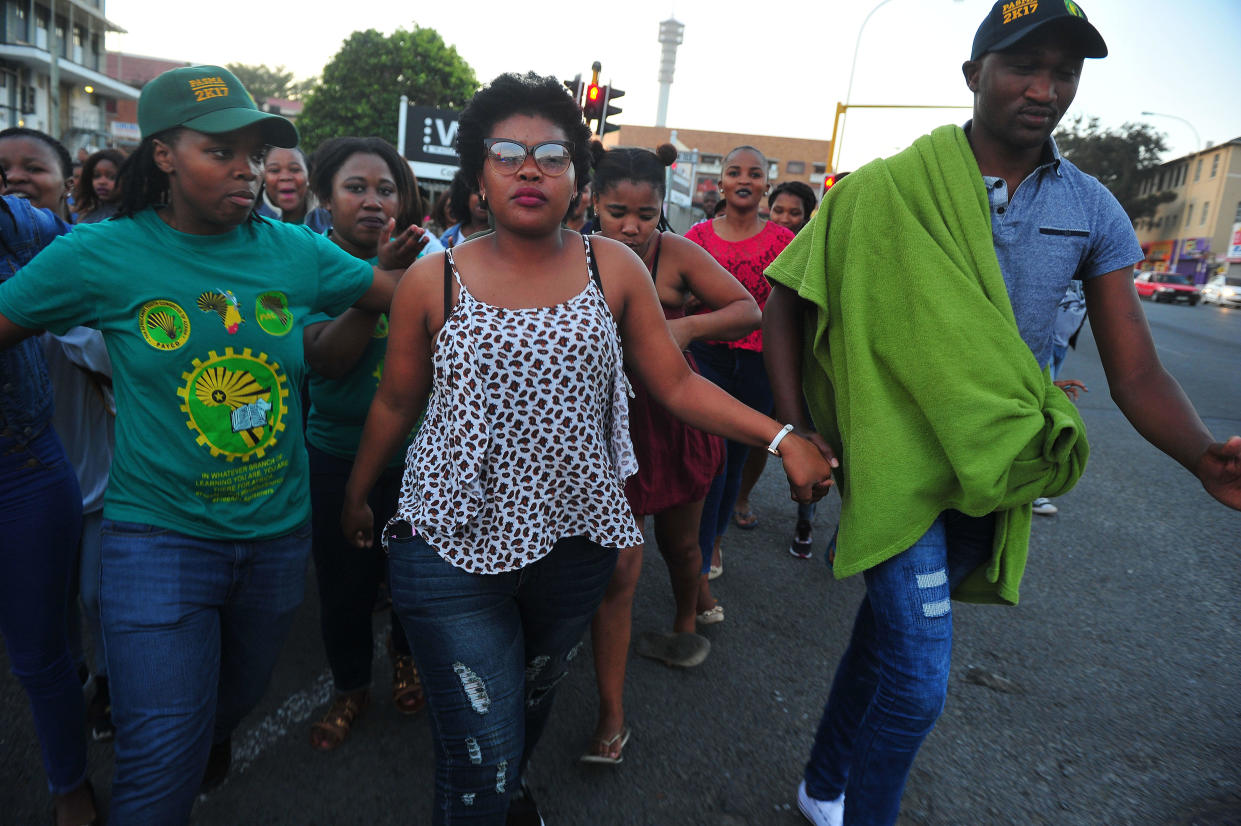 Sibongile Mani, center, is seen fleeing a media conference as angry students demand that she pay back National Student Financial Aid Scheme (NSFAS) money she spent after a clerical error dumped $1 million in her bank account, in a September 4, 2017 file photo taken in East London, South Africa. / Credit: Foto24/Getty